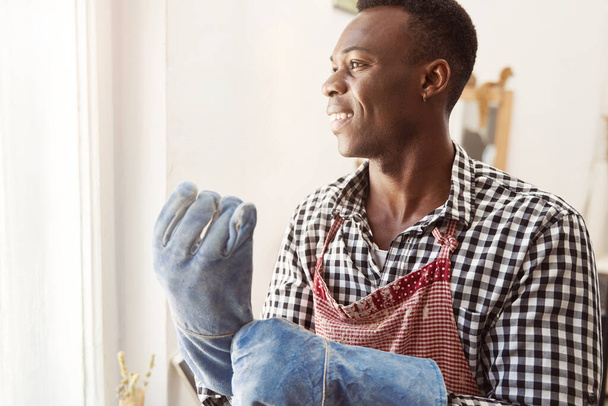 Joyous ceramist putting on his work gloves - Foto, imagen