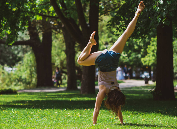 Happy woman enjoy the life and having fun, and take a gymnastic at city park. Summer sunny days and good mood - Fotó, kép