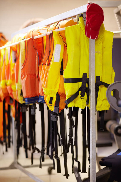 Готов, когда нужно. Обрезанный снимок спасательных жилетов, висящих на рельсах внутри спасательной станции. - Фото, изображение
