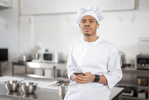 Latin chef with phone in professional restaurant kitchen - Фото, зображення