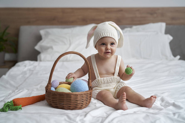 Little baby in rabbit costume sitting on bed at home  - Photo, Image