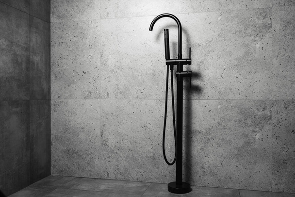 Black floor standing bath taps, on the background of dark grey bathroom walls. - Photo, Image