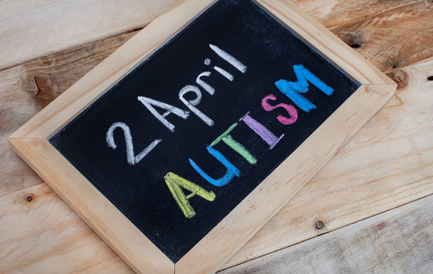 Слово Аутизм, написане вручну на дошці з блакитними шматочками головоломки
 - Фото, зображення