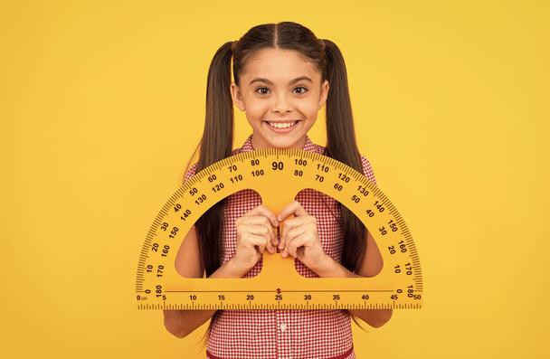 heureux adolescent fille tenir école mathématiques outil rapporteur règle sur fond jaune, géométrie - Photo, image