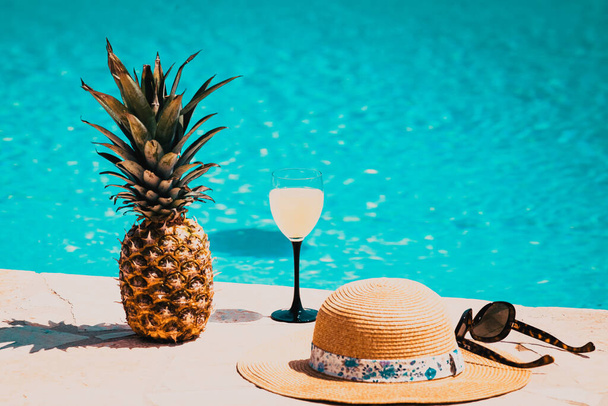 ψάθινο καπέλο cocktail και ανανάς δίπλα στην πισίνα - καλοκαιρινές διακοπές - Φωτογραφία, εικόνα