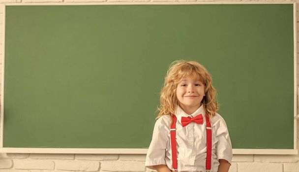 zurück zur Schule. Wissenstag. Konzept der Bildung. Nerd-Kind mit langen Haaren an der Tafel. - Foto, Bild