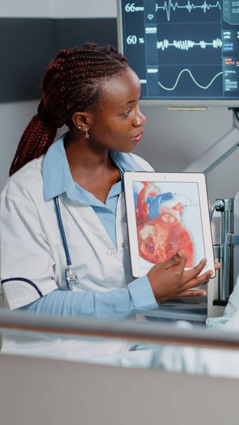 Medico che punta al tablet con l'immagine cardiologica in mostra - Foto, immagini
