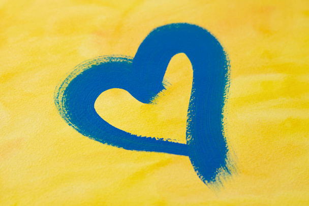corazón azul sobre un fondo amarillo, símbolo de independencia en Ucrania, guerra en Ucrania - Foto, Imagen