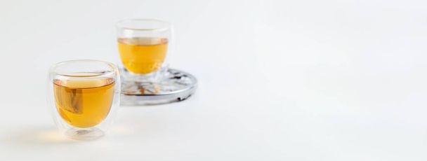 zöld tea átlátszó üvegpohárban, fém állvány fehér háttérrel, banner - Fotó, kép