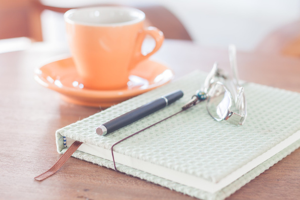 Notizbuch, Stift und Brille mit orangefarbener Kaffeetasse - Foto, Bild