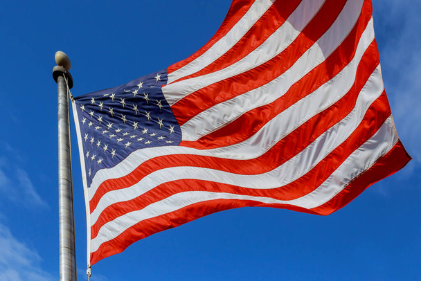 Teken van patriottisme van Amerikaanse vlag wapperend op vlaggenmast - Foto, afbeelding