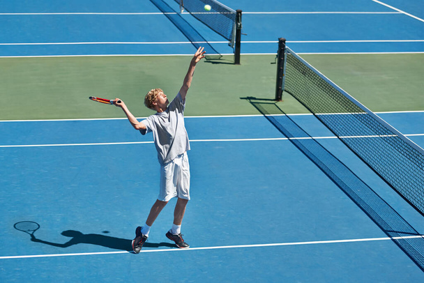 Helvetti on alku jonain päivänä. Kuvattu nuori poika pelaa tennistä aurinkoisena päivänä. - Valokuva, kuva