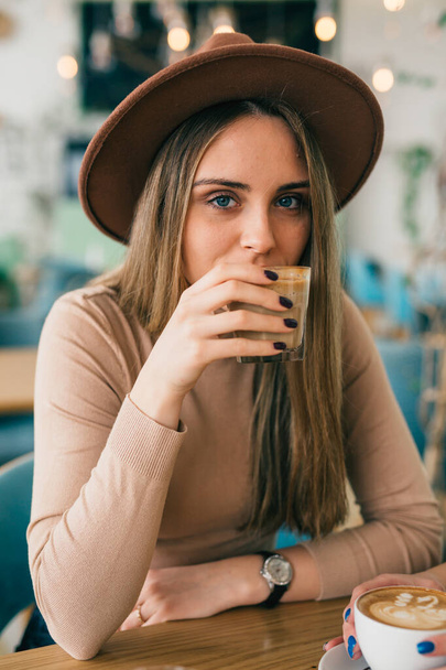 stylish woman drinking coffee in cafeteria - Фото, зображення