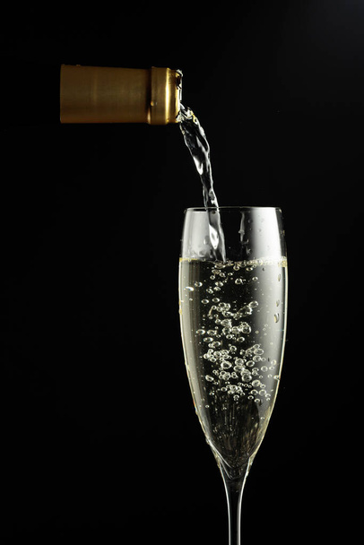 Sparkling wine is poured from a bottle into a glass. Copy space. - Фото, изображение
