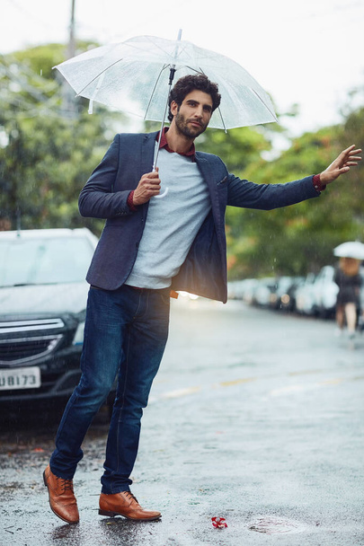 Taxi. Full length shot of a handsome young businessman on his morning commute in the rain. - Foto, Bild