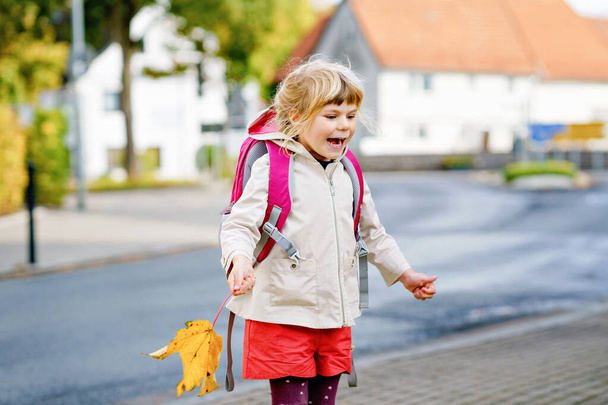 Cute little preschool girl on her first day going to playschool. Healthy happy child walking to nursery school. Kid with backpack going to day care on the city street, outdoors - Photo, Image