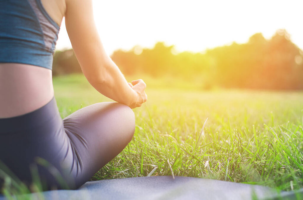 Vista posteriore di una donna che fa yoga in natura. Giovane donna seduta in posizione di loto al tramonto - Foto, immagini