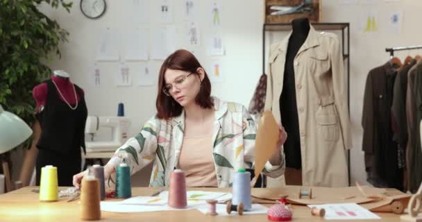 Het werk van modeontwerper en kleermakers in de winkel. Modeontwerpers werken in hun atelier. Kleurrijke stoffen, kleding opknoping en naaiwerk zijn zichtbaar. - Video