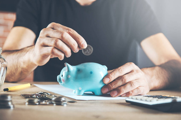 man hand piggy bank with coins on desk - Фото, зображення