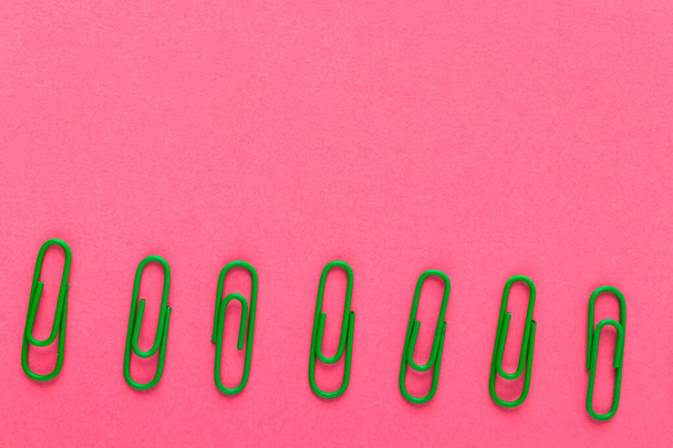 Colored paper clips. Green paper clips macro close up isolated on a pink background with copy space. - Foto, afbeelding