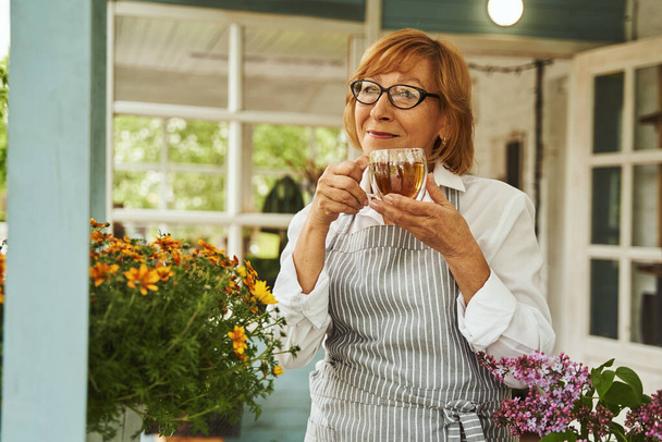 Joyful female relaxing with hot drink on terrace - Fotografie, Obrázek