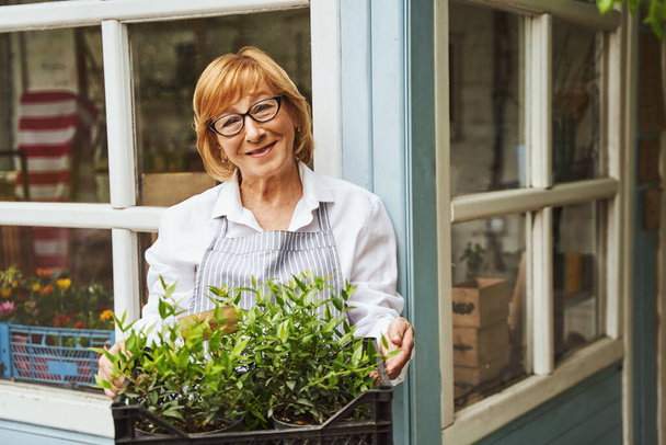Mujer envejecida alegre que cuida las plantas al aire libre - Foto, imagen