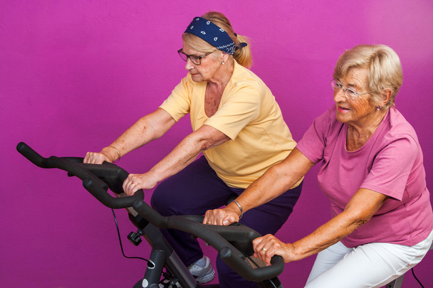 Ηλικιωμένες γυναίκες κάνει πόδι ασκήσεις στο γυμναστήριο. - Φωτογραφία, εικόνα