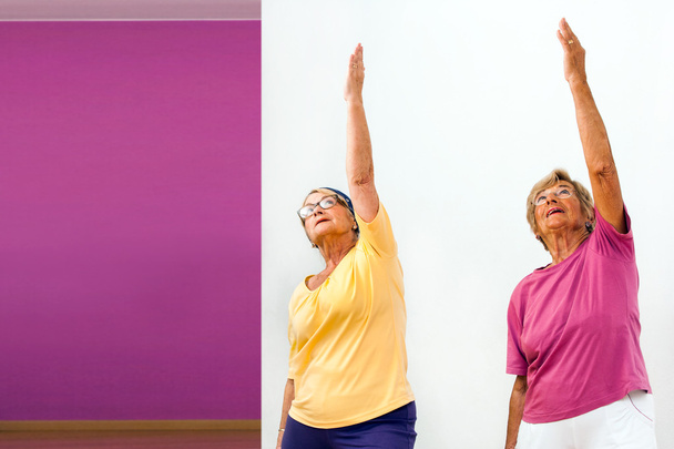 Starszych kobiet rozciąganie w siłowni. - Zdjęcie, obraz