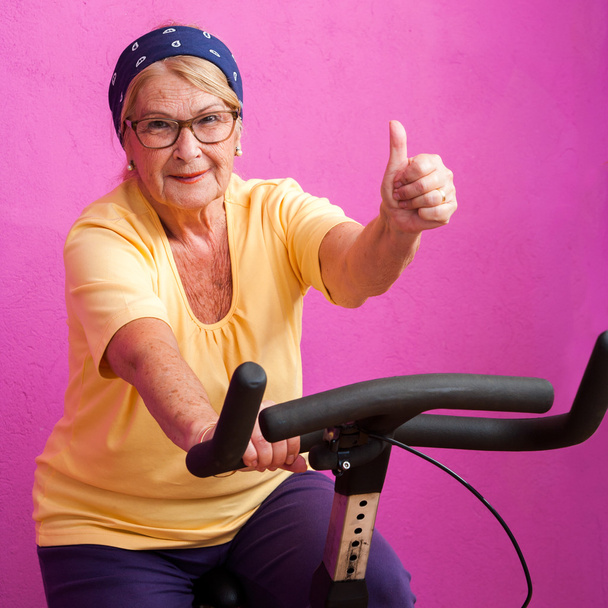 Подходит пожилая женщина, делающая большие пальцы на велосипеде
. - Фото, изображение