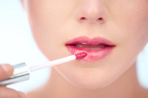 Pretty in pink. A young woman applying pink lipstick with an applicator. - 写真・画像