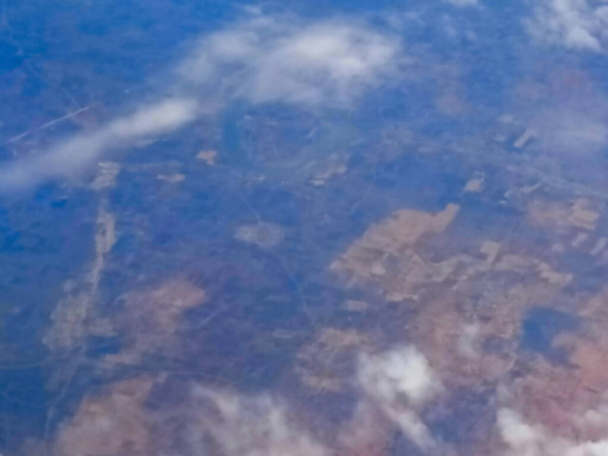 Θολή εικόνα του εναέριου τοπίου της Ινδίας, με ωραία λευκά σύννεφα στην ατμόσφαιρα, εικόνα που γυρίστηκε στον ουρανό από το αεροπλάνο. Φύση αρχείου εικόνας. - Φωτογραφία, εικόνα