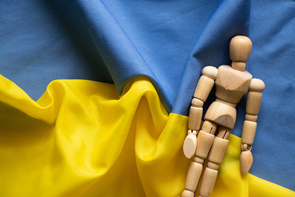 Ukrayna 'nın sarı ve mavi ulusal bayrağı arka plan ve ahşap adam, Ukrayna 2022' deki savaşı ve barışı durdurun. - Fotoğraf, Görsel