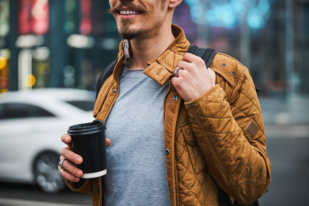 Smiling man drinking coffee in city centre - Фото, изображение