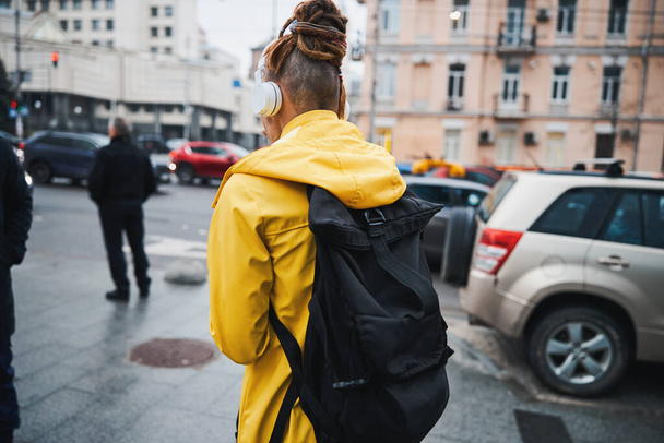 Guy walking with backpack and earphones outdoors - Zdjęcie, obraz