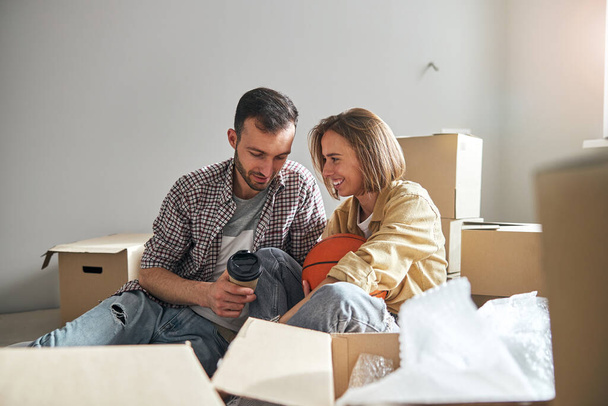 Ζευγάρι κάθεται στο πάτωμα ανάμεσα σε κουτιά χωρίς συσκευασία - Φωτογραφία, εικόνα