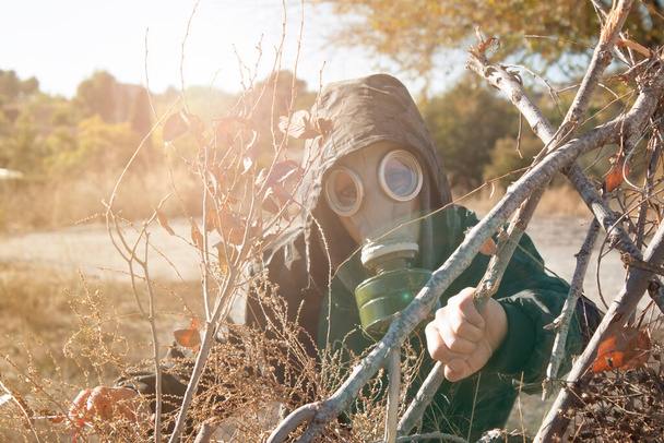 Wojskowa kobieta chowa się za gałęziami w masce gazowej. koncepcja wojny chemicznej. przestrzeń kopiowania - Zdjęcie, obraz