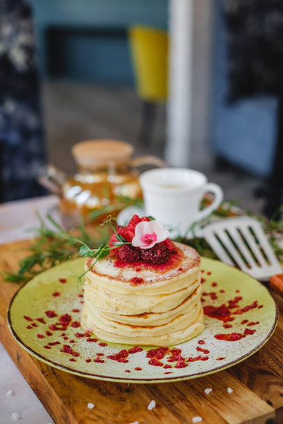 delicious pancakes with syrup in a stack and flower decoration on top a wooden table. - Photo, Image