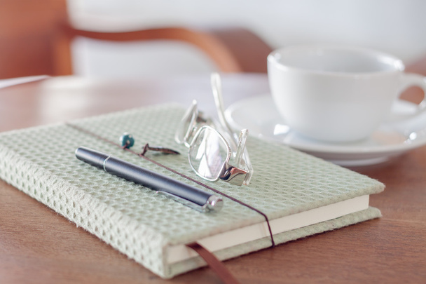 Zápisník s perem, brýle a bílý šálek na dřevěných kartu - Fotografie, Obrázek