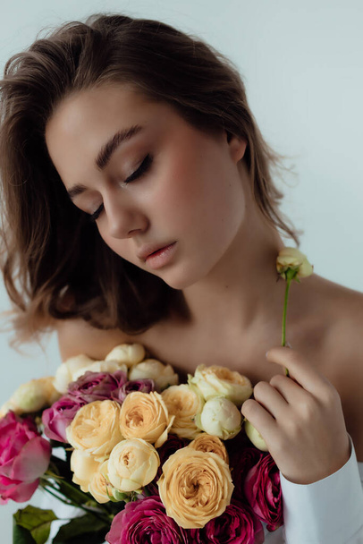 Beautiful girl model with a bouquet of roses. Spring Lady on light background. Female body and style concept. Advertisement or clothes sale design. Space of text - Foto, Imagem
