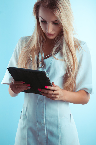 Color photo of beautiful blonde nurse reading on tablet - Foto, Imagen