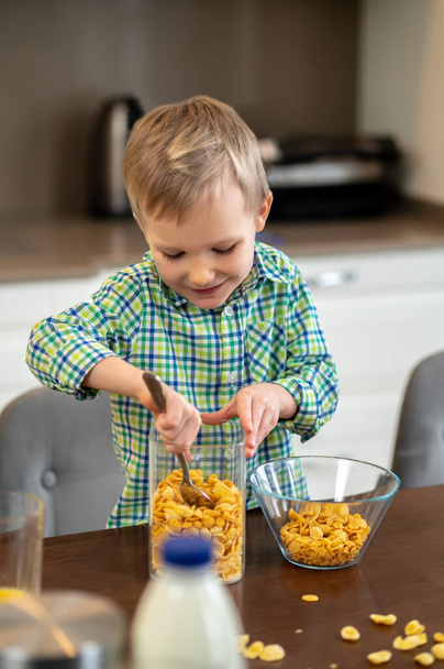 Joyous child scooping ingredients for an oatmeal dish - Zdjęcie, obraz