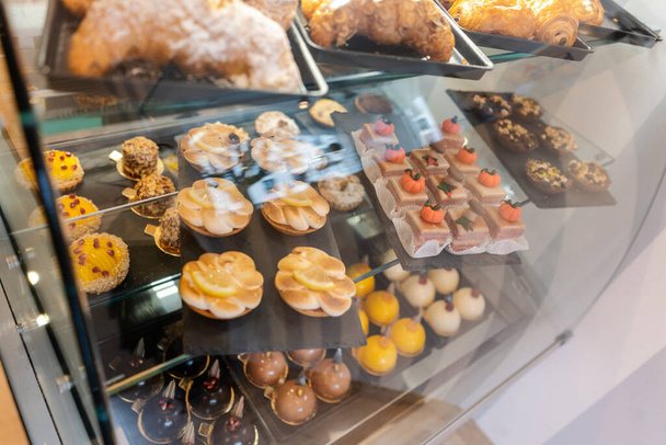 Confectioner shot through glass display in her shop - Photo, Image