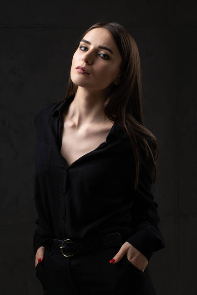 Portrait of a young brunette with long hair in the studio. Dramatic photo in dark colors. - Foto, immagini