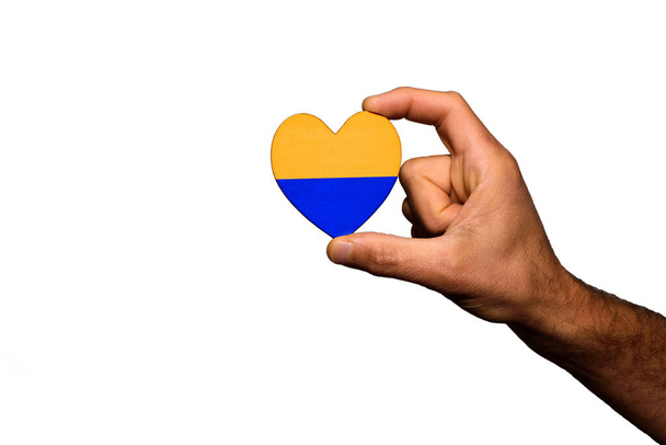 Το χέρι ενός άντρα κρατά την καρδιά του με τη σημαία του Ουκρανού στην επιθυμία για ειρήνη, απομονωμένο σε λευκό φόντο. - Φωτογραφία, εικόνα