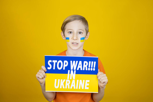 ένα αγόρι κρατά μια αφίσα μπροστά του με την επιγραφή σταματήσει τον πόλεμο στην Ουκρανία - Φωτογραφία, εικόνα
