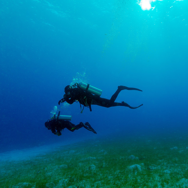 海の底の近くの 2 つのダイバーのシルエット  - 写真・画像