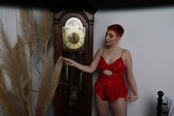 Photo of beautiful white model in a lingerie in a bedroom in front of a clock - Foto, immagini