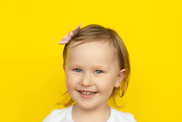 Happy Joyful laughter of little girl in white shirt on yellow background. - Photo, image