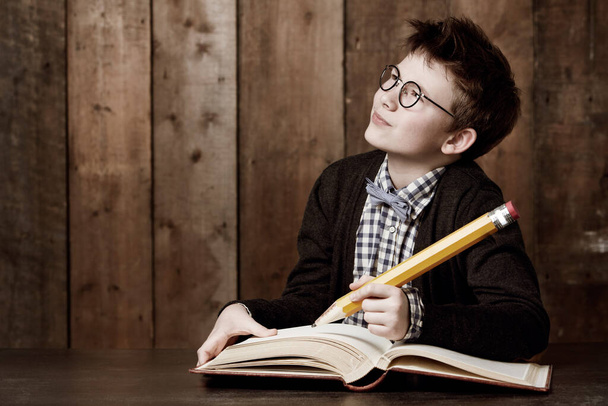 J'écris de grandes idées. Jeune garçon portant des lunettes et faisant ses devoirs avec un énorme crayon. - Photo, image
