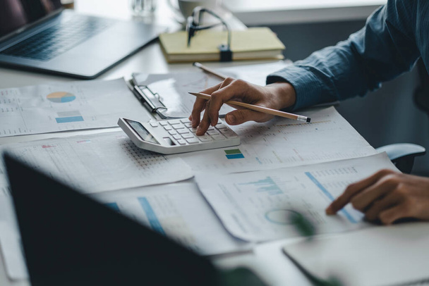 Крупним планом бізнесмен працює на столі за допомогою калькулятора аналізу фінансового обліку в офісі
 - Фото, зображення